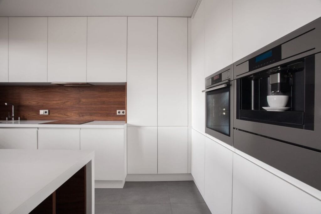 White kitchen cabinets with wood backsplash that adds contrast