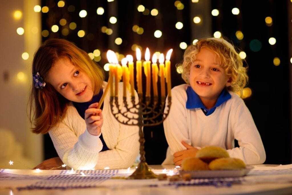 Kids lighting Hanukkah Menorah and celebrating the holiday