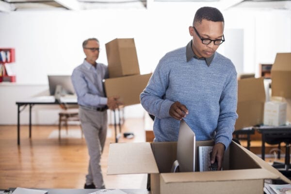 Multi-ethnic businessmen packing cardboard boxes in creative office