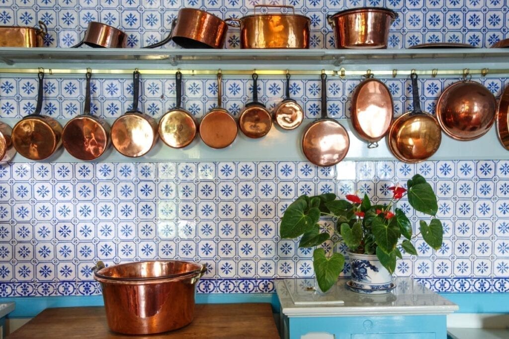 Kitchen with blue tile backsplash and copper pots and pans