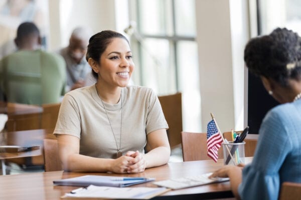 A cheerful mid adult female soldier smiles as she talks with a bank employee about a home loan.