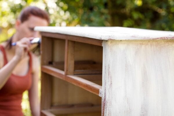 Woman painting old dresser to give it new life