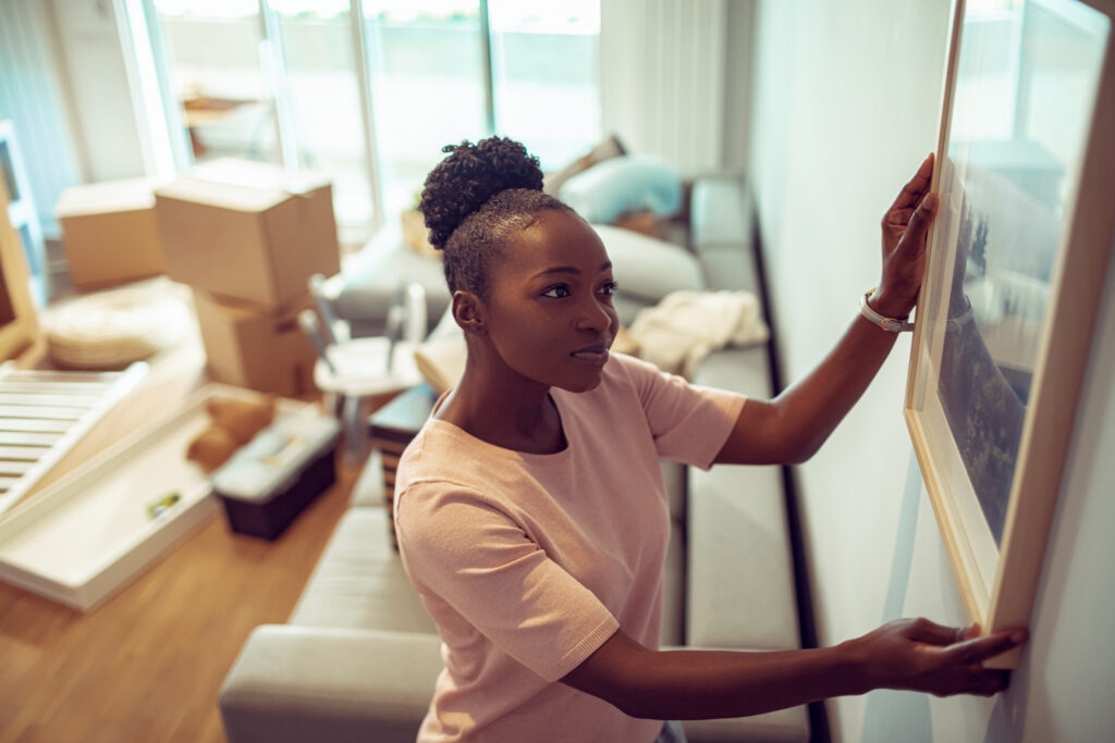 Close up of a young girl moving into her new home and putting up a painting on the wall