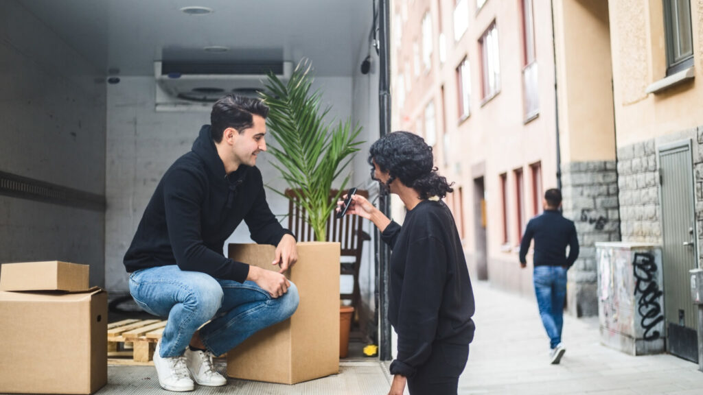 Female mover showing mobile phone to coworker by truck