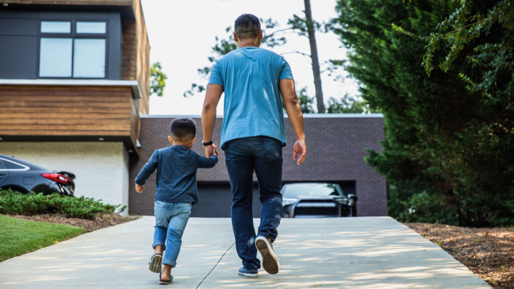 Father walking up driveway with son