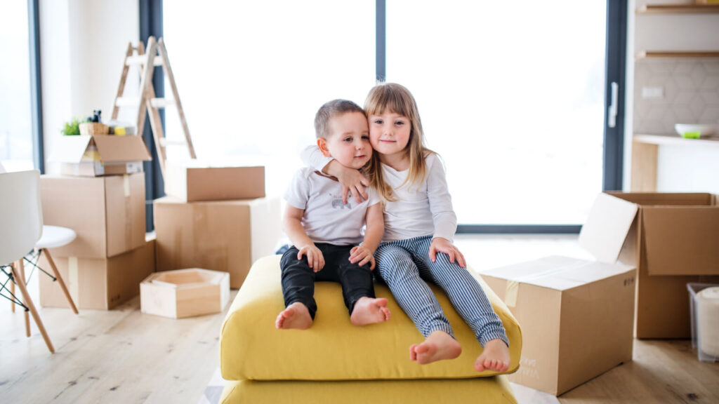 Front view portrait of two small children sitting when moving in a new home