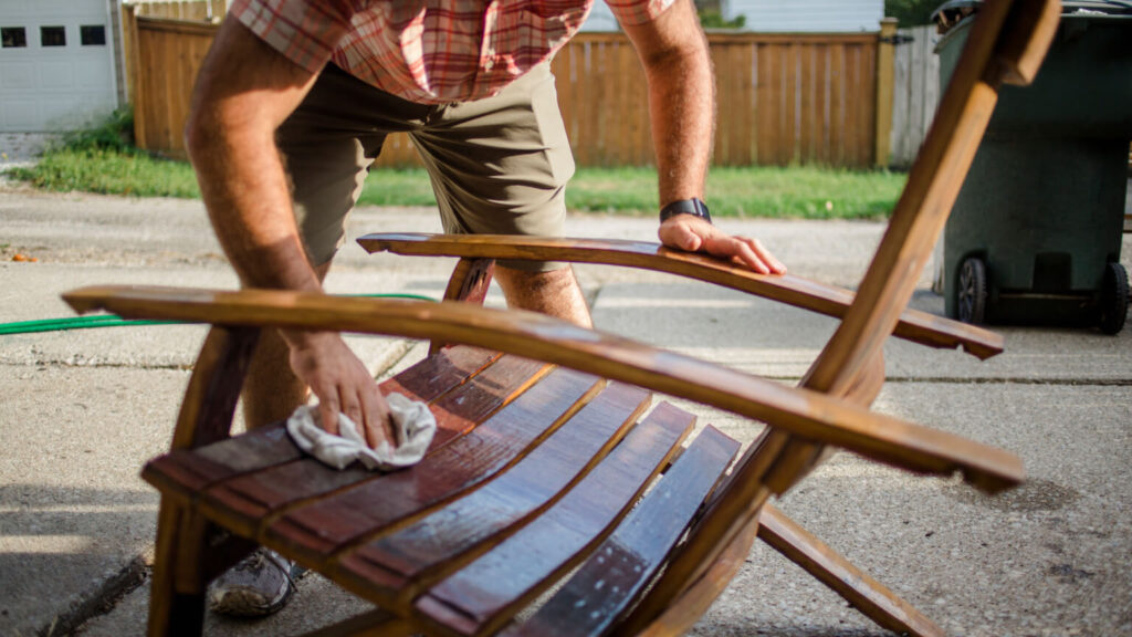 A craftsman polishes a handmade wooden chair outside