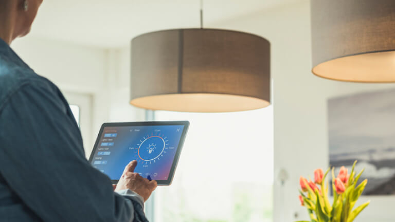 Woman operating lighting equipment through digital tablet at home