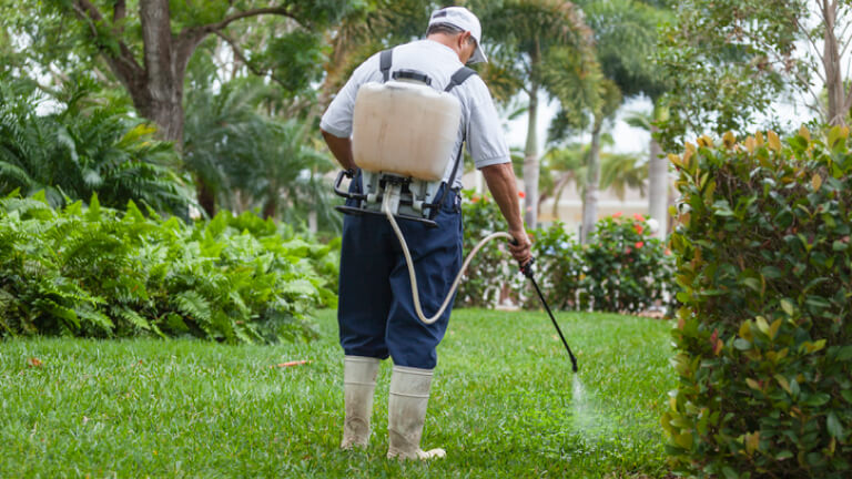 est control technician with portable spray rig using spray nozzle and hose