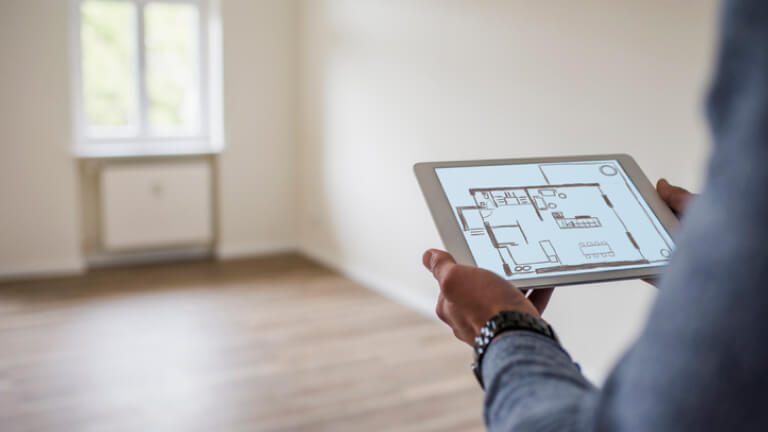 an in new home holding tablet with floor plan