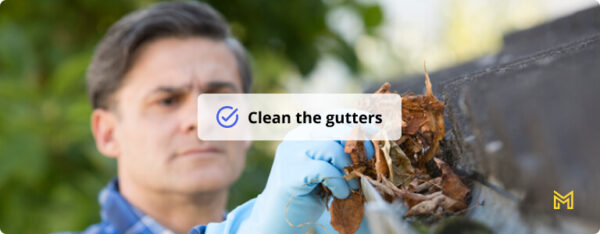 Man Clearing Leaves From Guttering Of House