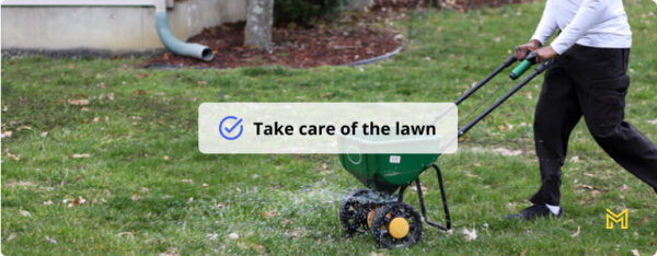 A African-American man using a seed and fertilizer spreader on a front lawn