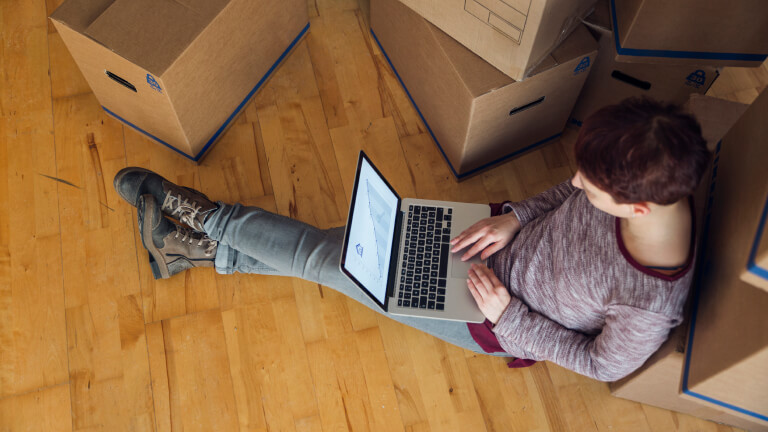 Person using laptop with rising line graph on the screen in a new home