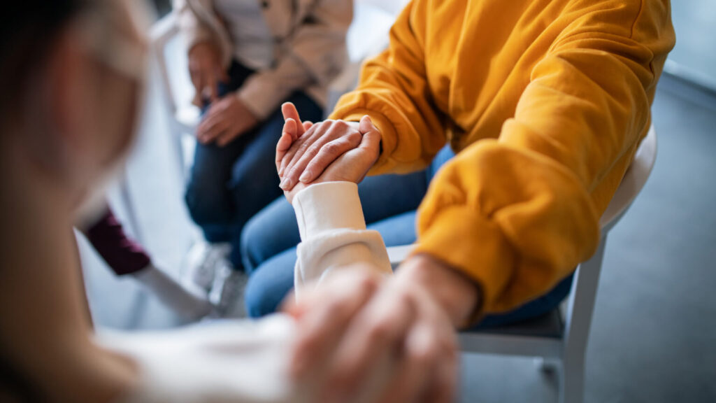 Unrecognizable depressed woman on group therapy, counseling concept.