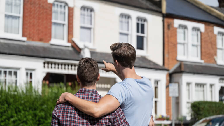 Male couple admiring two-story house in their neighbourhood