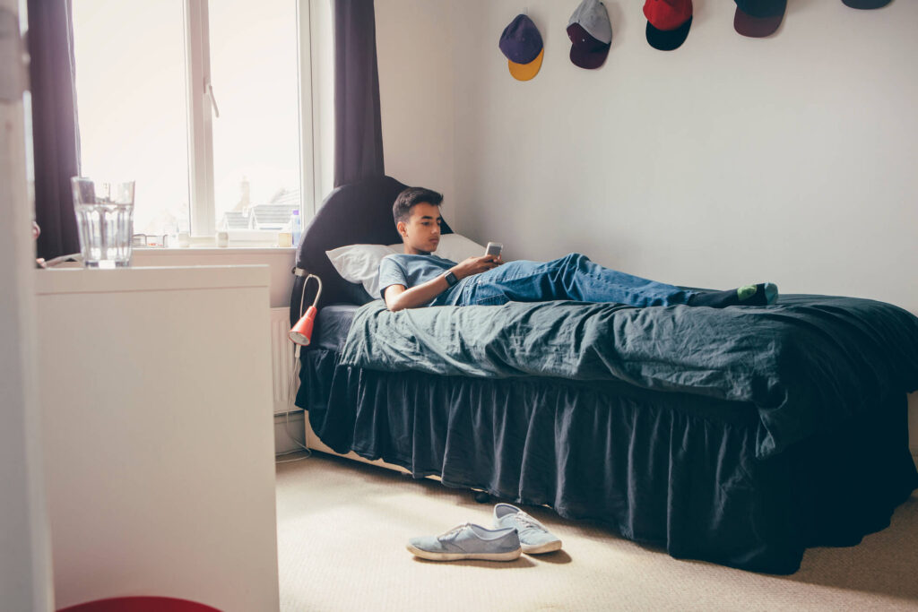 Teenager sitting on twin mattress