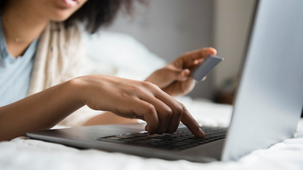 Woman laying in bed online shopping with laptop
