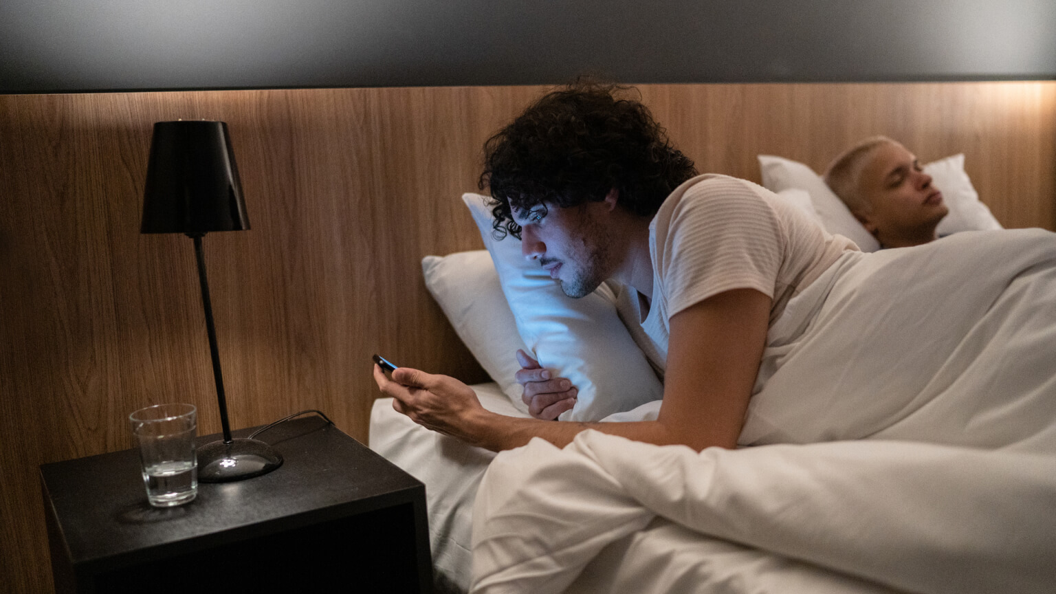 Young man checking smartphone at bed