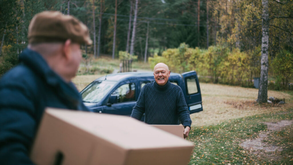 Smiling homosexual couple carrying boxes while relocating in house