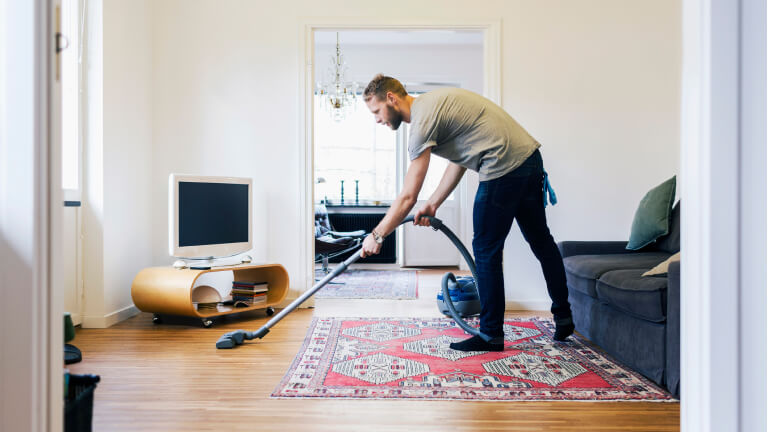 Side view of man vacuuming hardwood floor