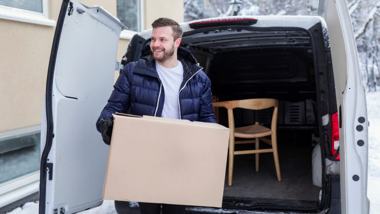 Smiling man carrying cardboard box