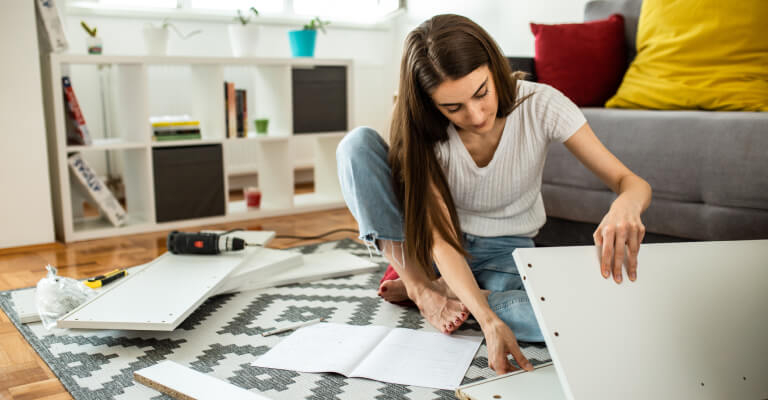 Woman assembling flat pack furniture at home